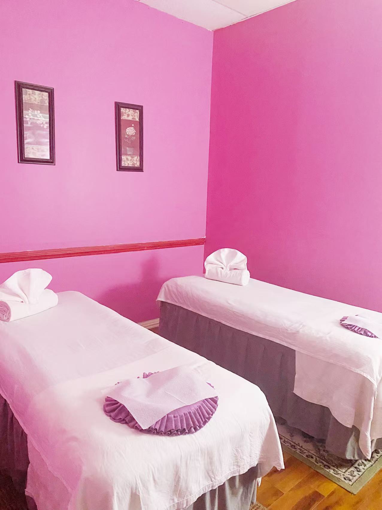Two massage tables made up with towels in a pink treatment room