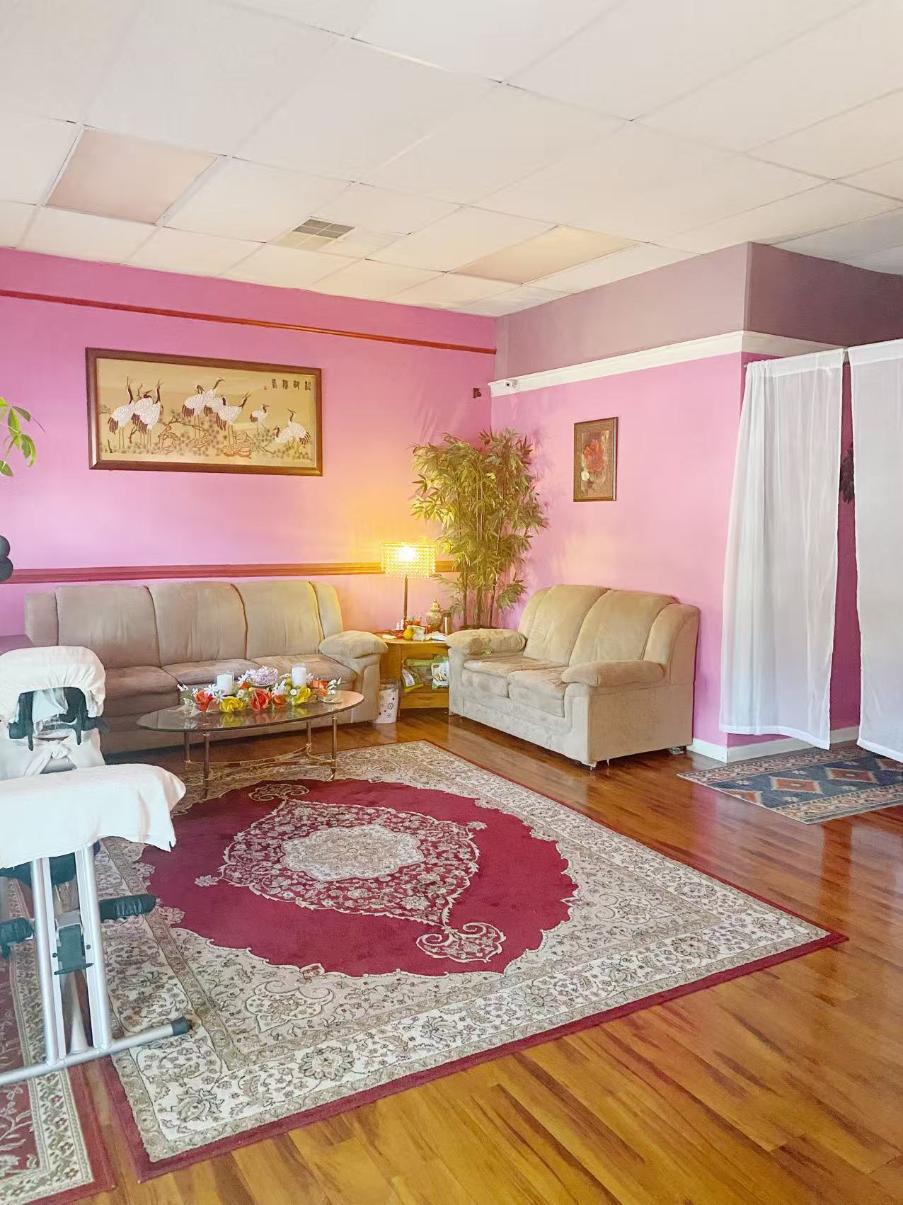 The waiting lounge with cream sofas, a red rug and pink walls
